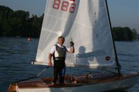 Segler in OK-Jolle prostet mit einem Bier dem Fotografen zu