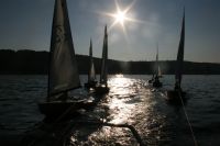 OK-Jollen in einem Schlepp hinter Motorboot in der Abendsonne