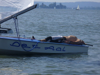 Segler nimmt auf einer Jolle ein Sonnenbad